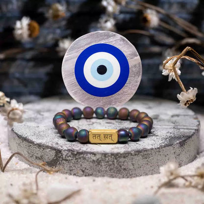 Bracelet with evil eye design on a round stone surface with dried flowers.
